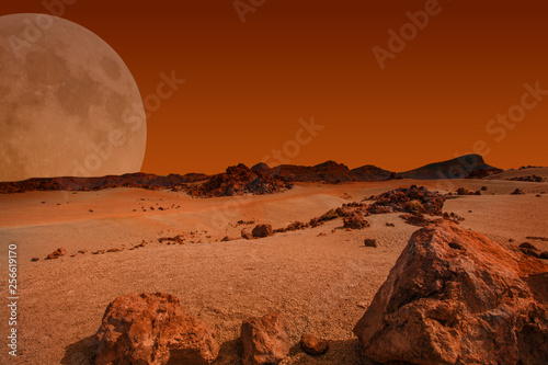 Red planet with arid landscape, rocky hills and mountains, and a giant Mars-like moon at the horizon, for space exploration and science fiction backgrounds. Elements of this image furnished by NASA.
