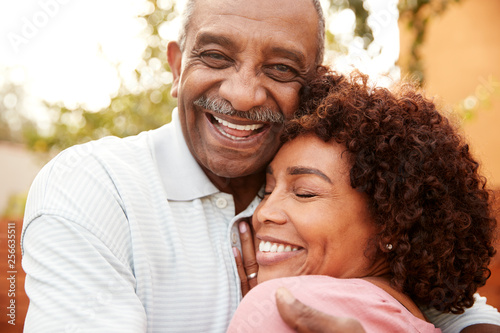 Senior black man and his middle aged daughter embracing, close up