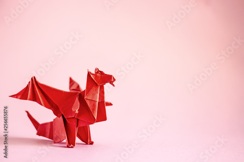 Origami dragon in red on a plain background. Paper Origami. Сopy space