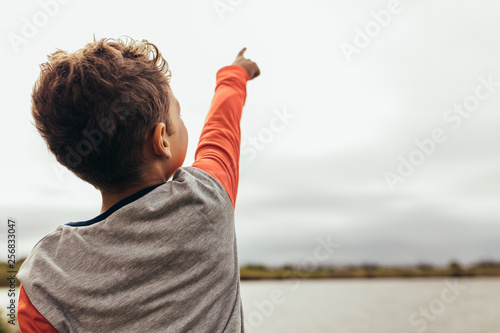 Portrait of a boy pointing towards the sky