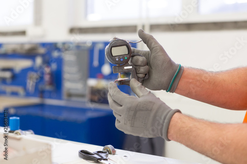 Measuring thickness of the paper sheet with digital micrometer at the printing plant