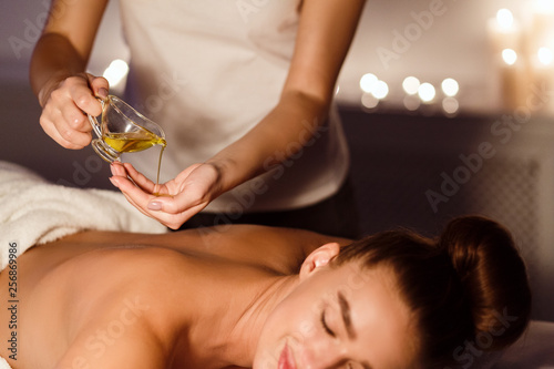 Masseur pouring aroma oil on hand, preparing for massage