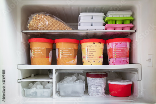 Full of bucket container ice creams flavors and ice cubes in freezer get ready for summer.