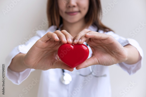 Young female doctor with the stethoscope holding red heart, cardiolog healthy care concept