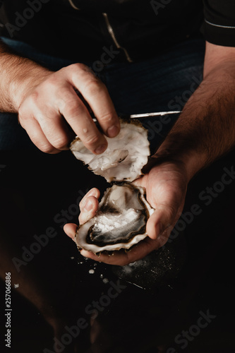 hands open the oyster with a knife