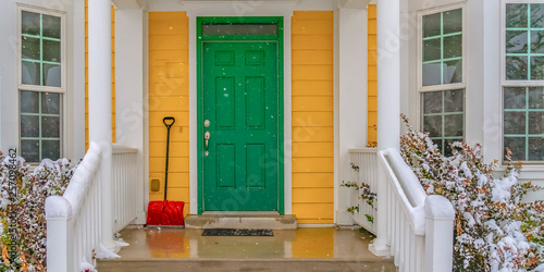 Snow showel beside the green front door of a home