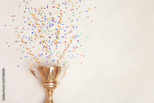 Trophy and confetti on light background, top view with space for text. Victory concept