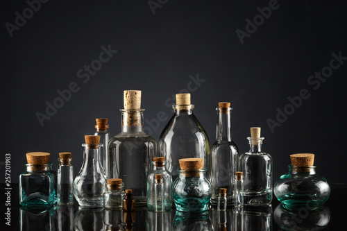 Glass bottles of different shapes and sizes on a black background.