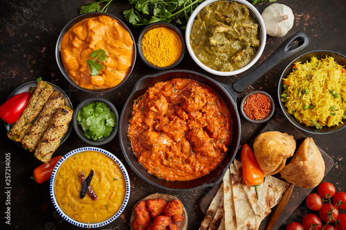 Assortment of various kinds of Indian cousine on dark rusty table