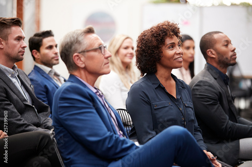 Group Of Businessmen And Businesswomen Listening To Presentation At Conference