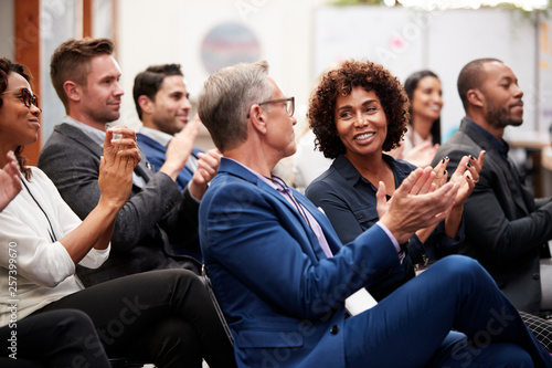 Group Of Businessmen And Businesswomen Applauding Presentation At Conference