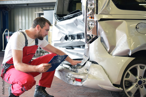 Begutachtung Unfallwagen in einer Autowerkstatt durch Mechaniker // Inspection of accident vehicles in a garage by a mechanic