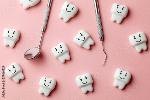 Healthy white teeth are smiling on pink background and dentist tools mirror, hook.