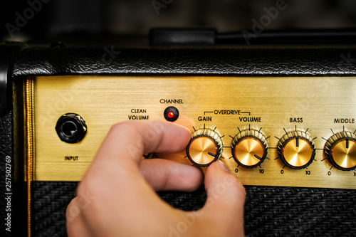 Guitar electric amplifier. Hand turning volume control knob up to the max. Rock music overdrive effect