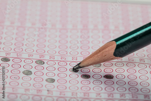 high school or university student hands taking exams, writing examination on paper answer sheet optical form of standardized test on desk doing final exam in classroom. Education literacy concept. 