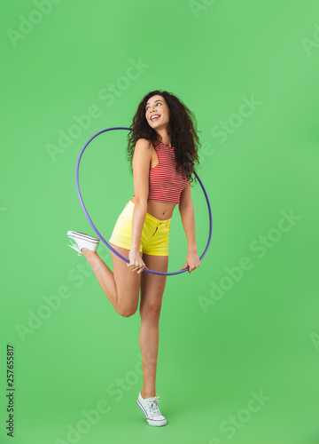 Photo of caucasian woman 20s wearing summer clothes doing exercises with hula hoop during workout