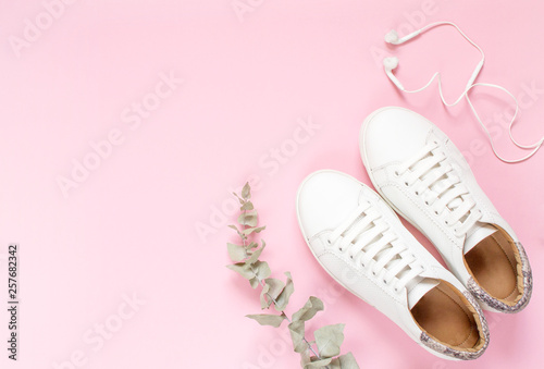 White sneakers on pastel pink background. Flat lay, top view minimal background