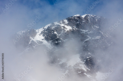 Landscape with beautiful rocks and dramatic cloudy sky at snowy mountain