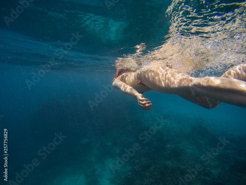 young woman swimming and snorkeling with mask and fins in clear blue water