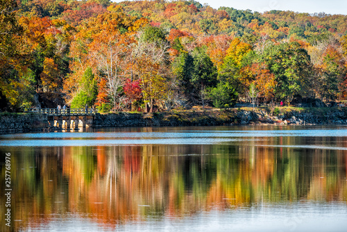 Great Falls trees reflection during autumn in Maryland colorful yellow orange leaves foliage by famous Billy Goat Trail people walking hiking on bridge