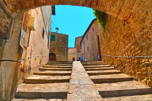 The narrow stone street with steps and arch in the historical center of Castiglione della Pescaia, Grosseto Tuscany, Italy