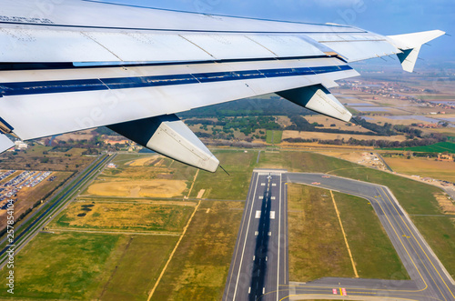 Looking through window aircraft at wing of airplane flying over the fiumicino where is situated the Fiumicino International Airport "Leonardo da Vinci.