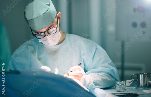 work of the surgeon in the hospital operating room. concentrated doctor with glasses.