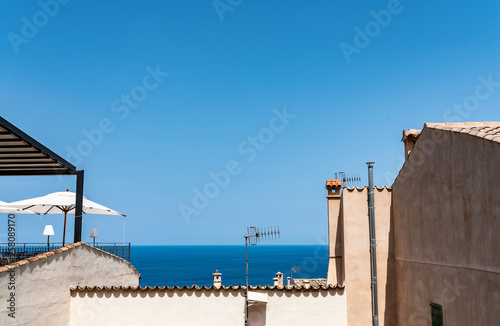 blue sky and ocean above rooftops of typical old houses in spanish village