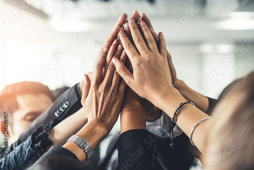 Many happy business people raise hands together with joy and success. Company employee celebrate after finishing successful work project. Corporate partnership and achievement concept.