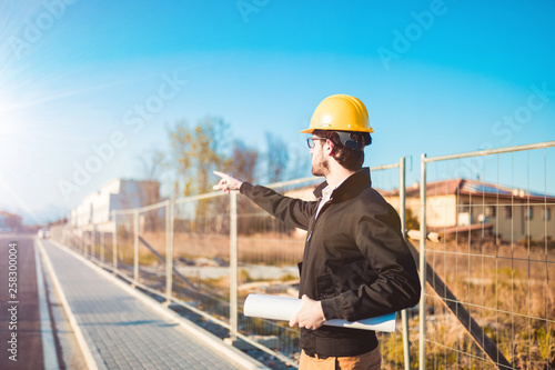Ingegnere da ordini agli operai, indica con il dito per eseguire i lavori correttamente prima di proseguire l'ispezione nel cantiere. Casco giallo di sicurezza,.