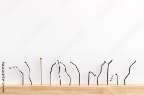 One golden nail among bent nails on white background.