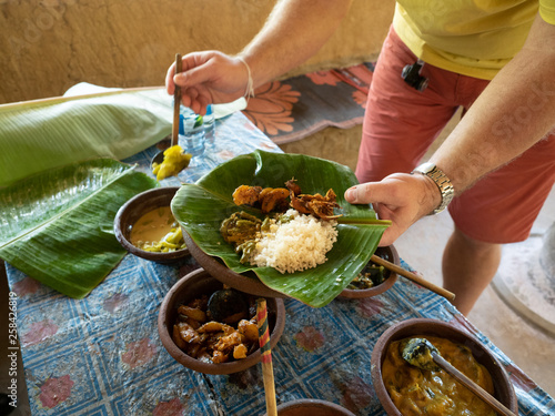 Male hands with rice and curry served in traditional rural kitchen. Eco village Hiriwadunna, Sri Lanka, March 10, 2019.