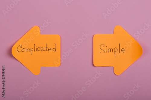 life choice - orange stickers in the form of index arrows with text Complicated and Simple on pink background