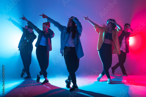 Animation group of young women and men dancing over red and blue dual color light on dark background