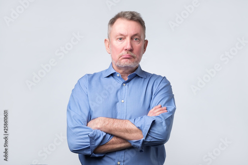 Serious senior man in blue shirt with folded arms