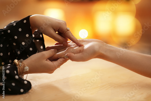 Chiromancer reading lines on woman's palm at table, closeup