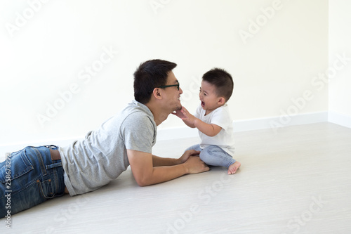 Asian father and son playing and smiling on floor in the room, Family having fun and laughs concept