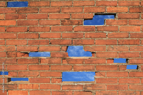 Backsteinmauer mit Lücken Löcher Himmel blau Hintergrund