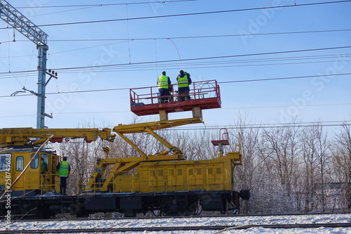 Special train with a landing crane for service and repair of electrical networks on the railway. Workers doing service work on electric lines over the rails