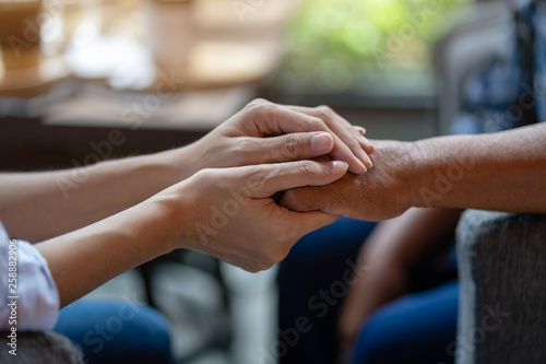 Hand of younger woman holding hand elderly woman, Helping hands, Take care for the elderly concept.