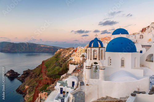 Amazing sunrise view of traditional white houses in Oia village on Santorini island, Greece.