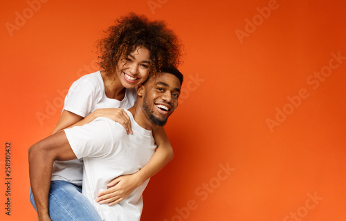 Happy african-american man and woman riding piggyback