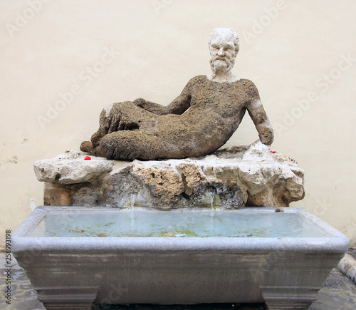 the fountain with funny marble stone statue of Satyr and a marble bath on a Roman street