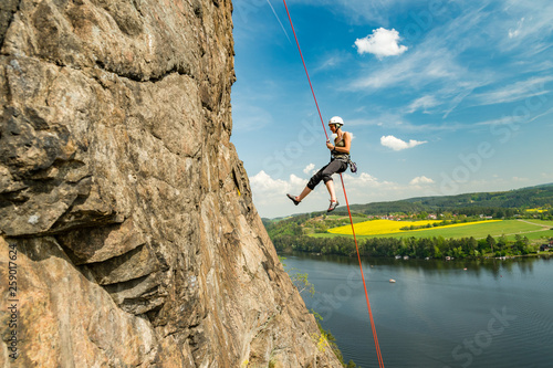 Girl abseiling above Vltava river on beautiful sunny day, Czech republic