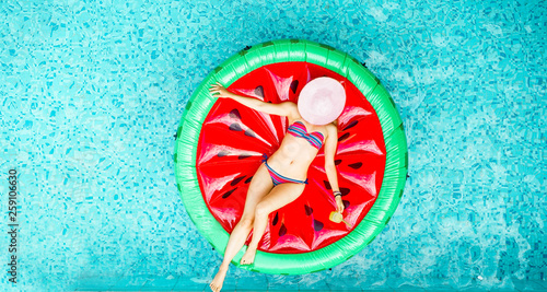 Young woman relaxing on watermelon lilo in villa resort pool