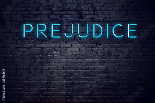 Brick wall and neon sign with text prejudice