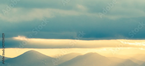 Mountains silhouetted in late afternoon light with storm clouds overhead