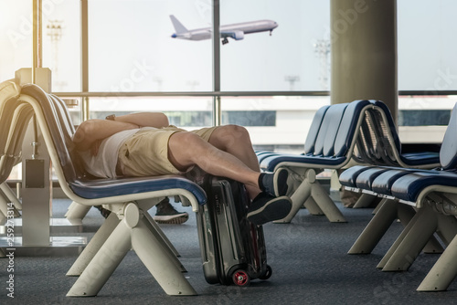 passenger of the aircraft tired and sleep on the chair in the transit hal of the airport terminal, waiting for the next schedule of the airplane