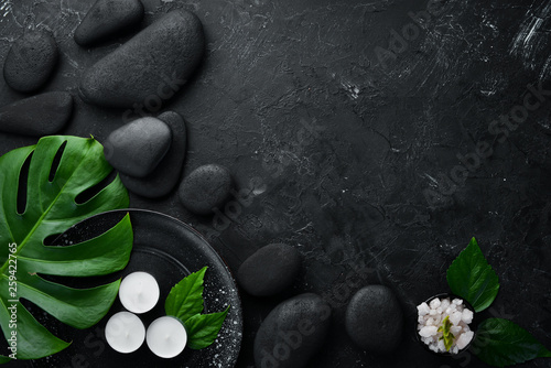 Zen stones and leaves with water drops. Spa background with spa accessories on a dark background. Top view. Free space for your text.