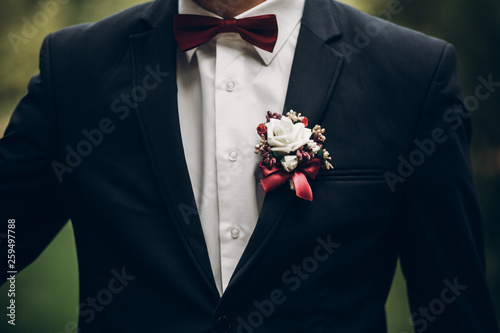 groom or groomsmen closeup, bow tie and boutonniere on suit, confident stylish man